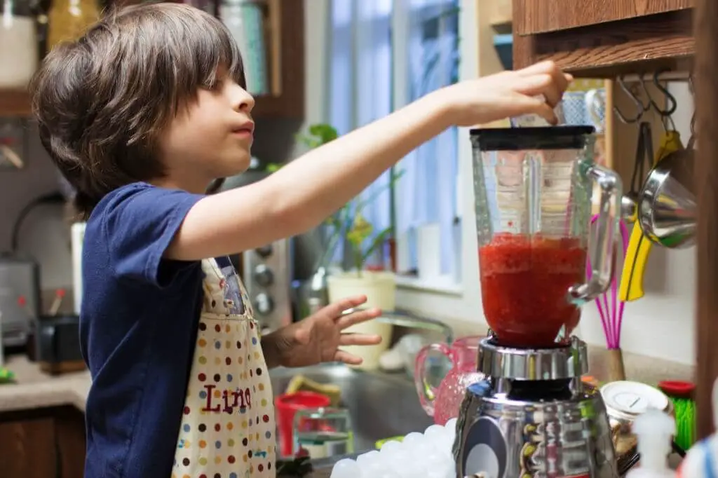 a young boy using a blender in the kitchen